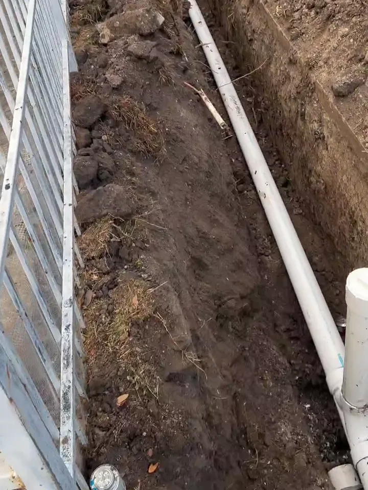 New white PVC drain line laid in a trench beside a Houston house, the pipe we use for cast iron pipe replacement