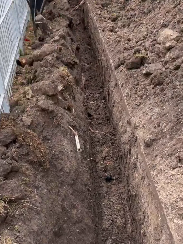 Open trench dug beside a Houston slab house, the kind of outside dig that reaches the drain lines in cast iron pipe replacement
