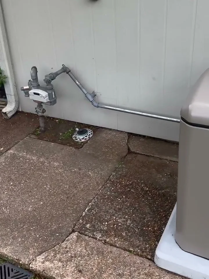 Natural gas regulator and gas line feeding a standby generator beside a concrete walk in Houston
