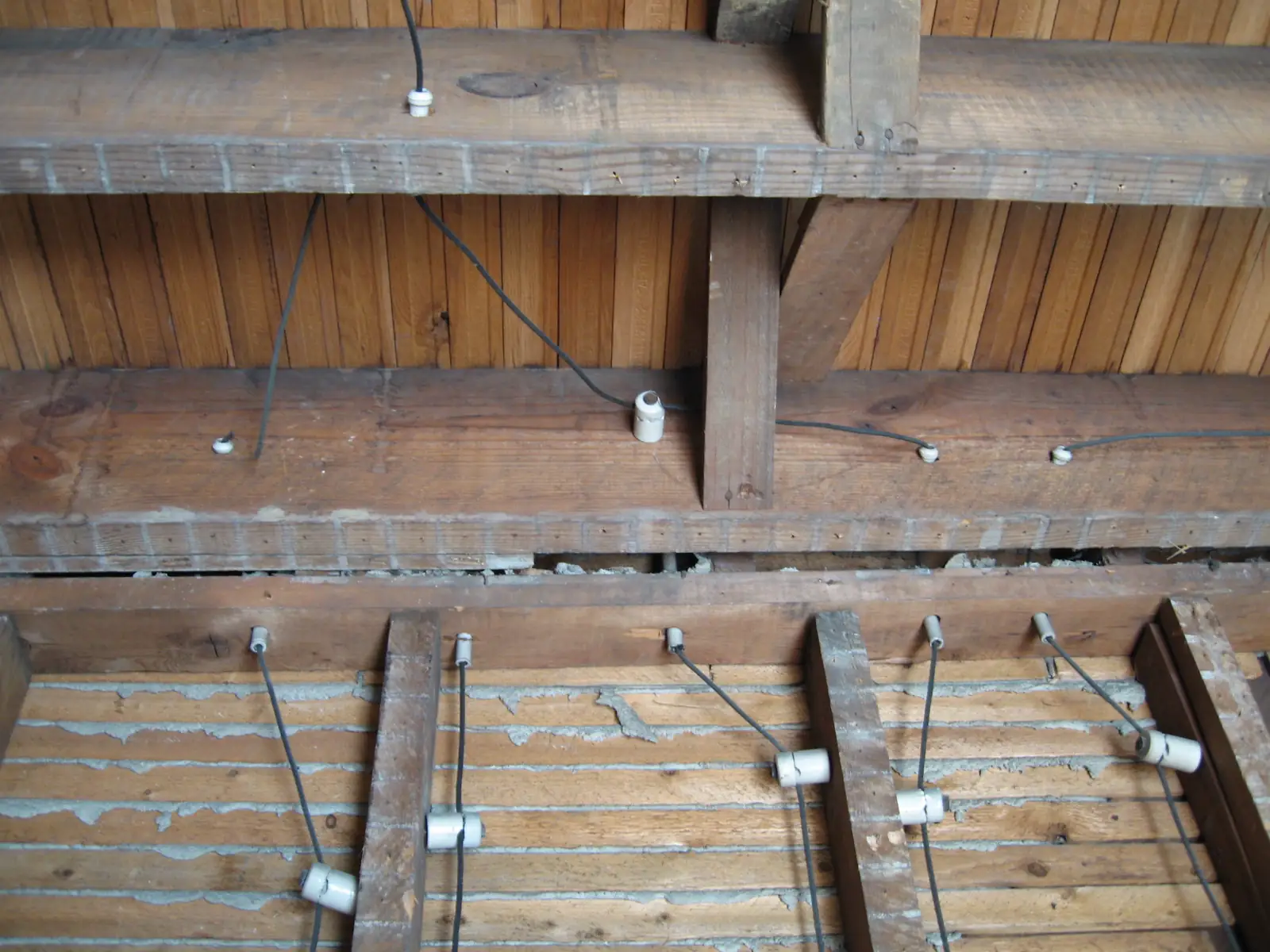 Knob and tube wiring on porcelain knobs across old floor joists, the kind replaced in a house rewiring