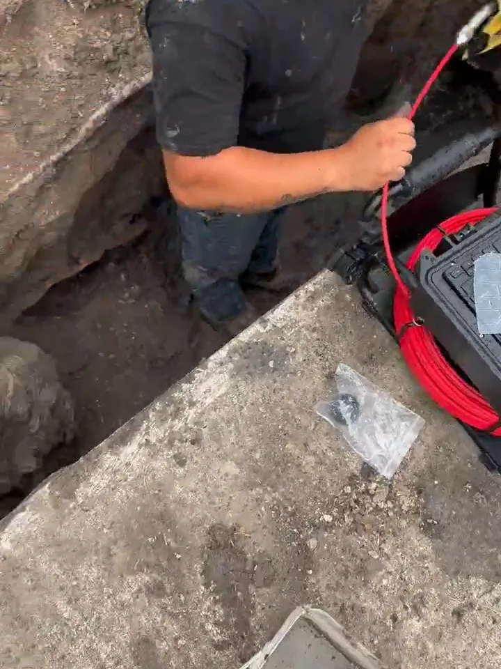 Our crew feeding the sewer camera cable into the line from an open trench during a sewer camera inspection in Houston