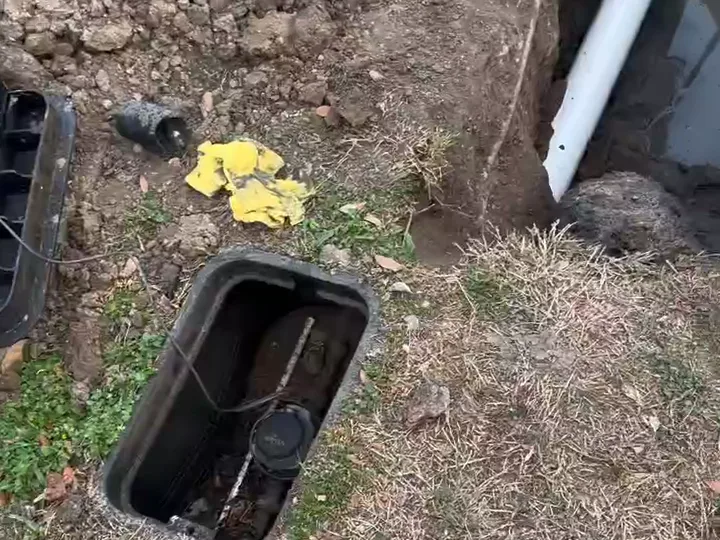 Open water meter box beside a trench with new white PVC pipe at a Houston home