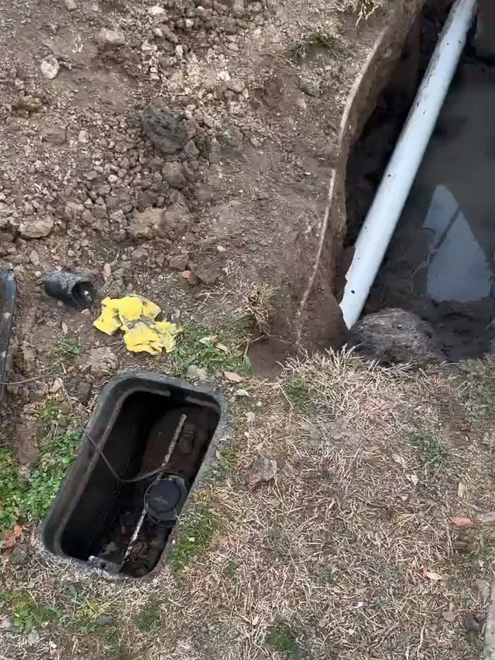 New white PVC sewer line tied in under the edge of a concrete slab from an outside pit, camera cable beside it, during slab leak repair in Houston